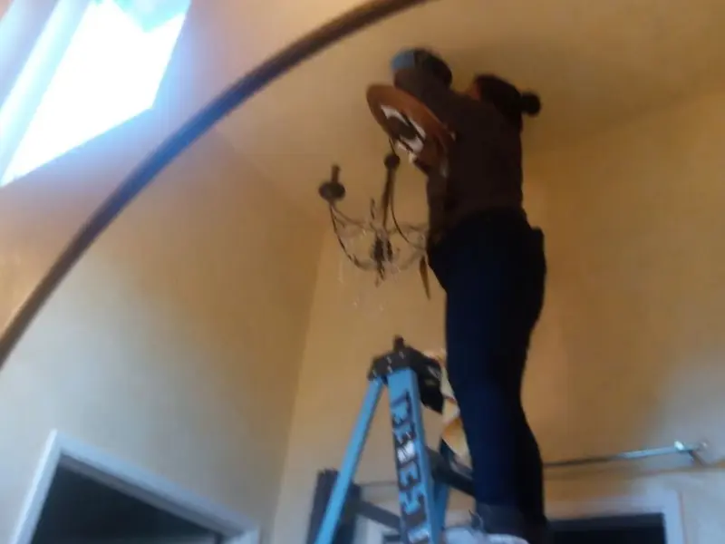 Electrician installing a chandelier in a The Village residence